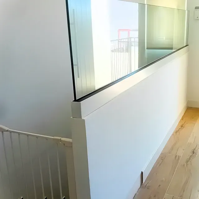 Un pasillo con escaleras y barandilla de cristal.