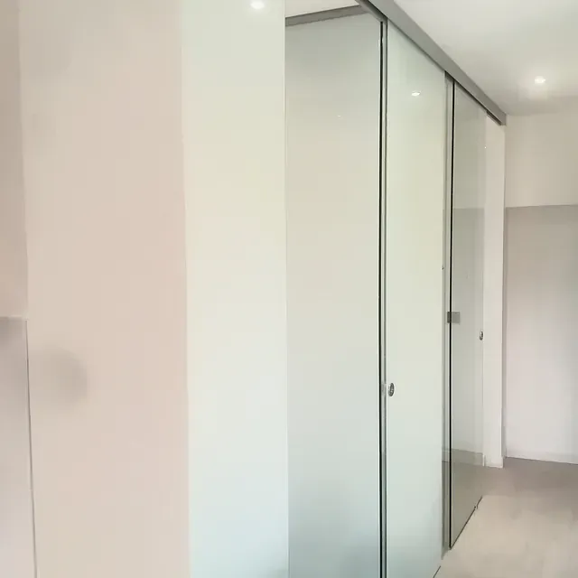 Un pasillo con puertas corredizas de vidrio y paredes blancas.