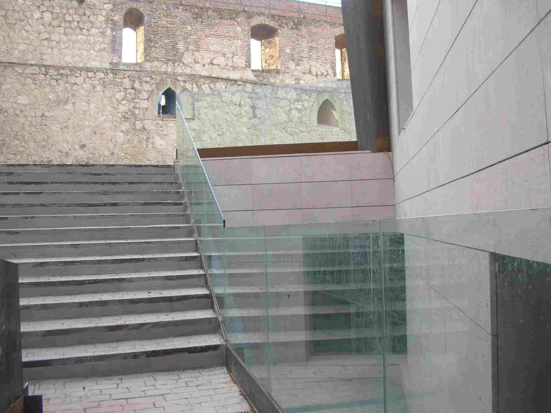 Escaleras que conducen a un edificio con barandilla de cristal.