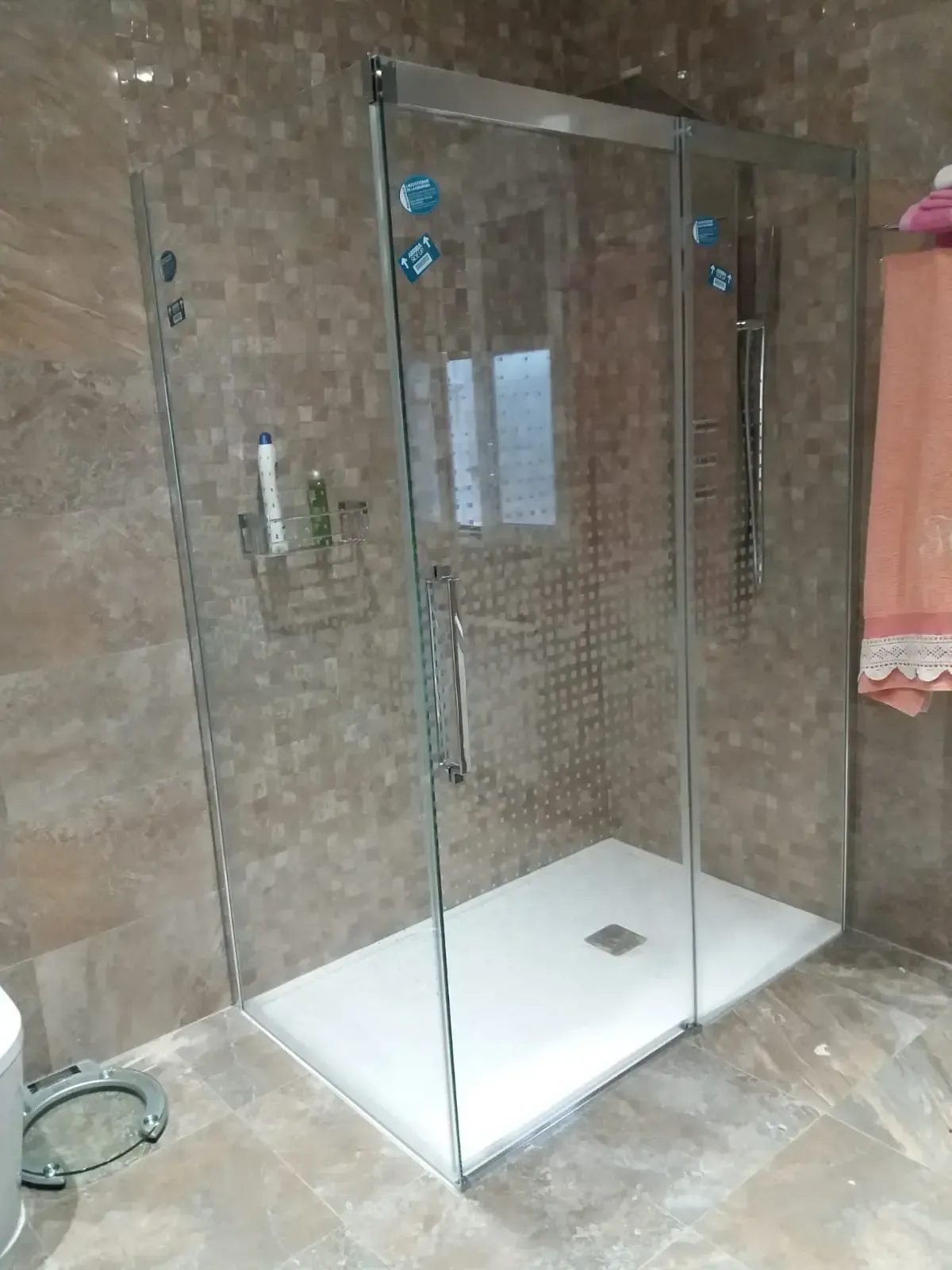 Un baño con ducha a ras de suelo con puertas corredizas de cristal.
