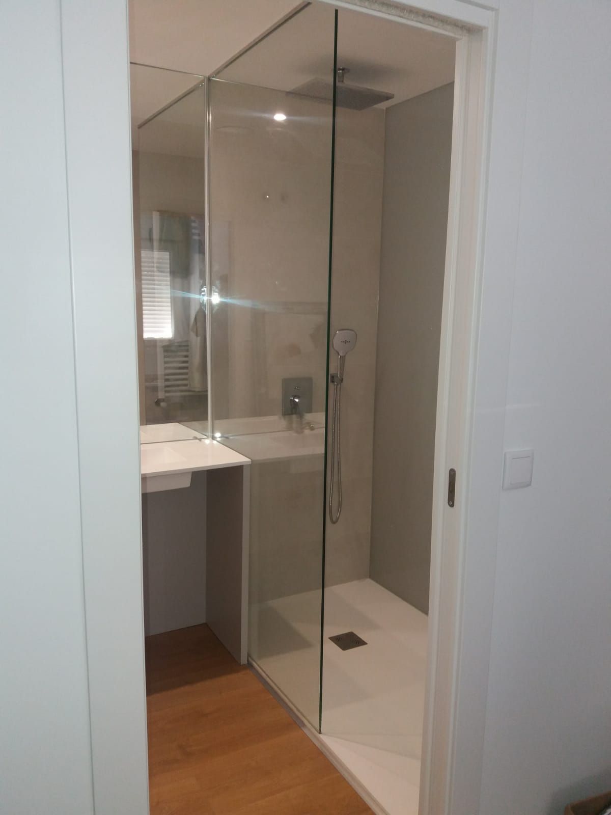 Un baño con ducha a ras de suelo y lavabo.