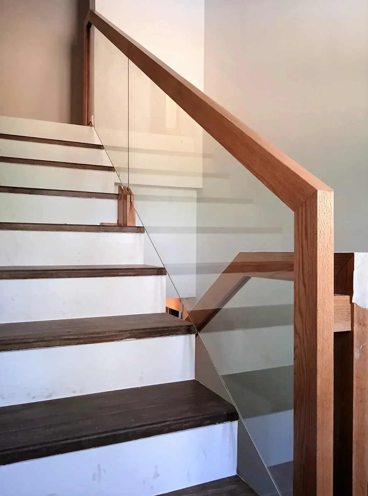 Una escalera con barandilla de madera y barandilla de cristal