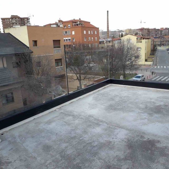 Una vista de una ciudad desde un balcón con barandilla de cristal.