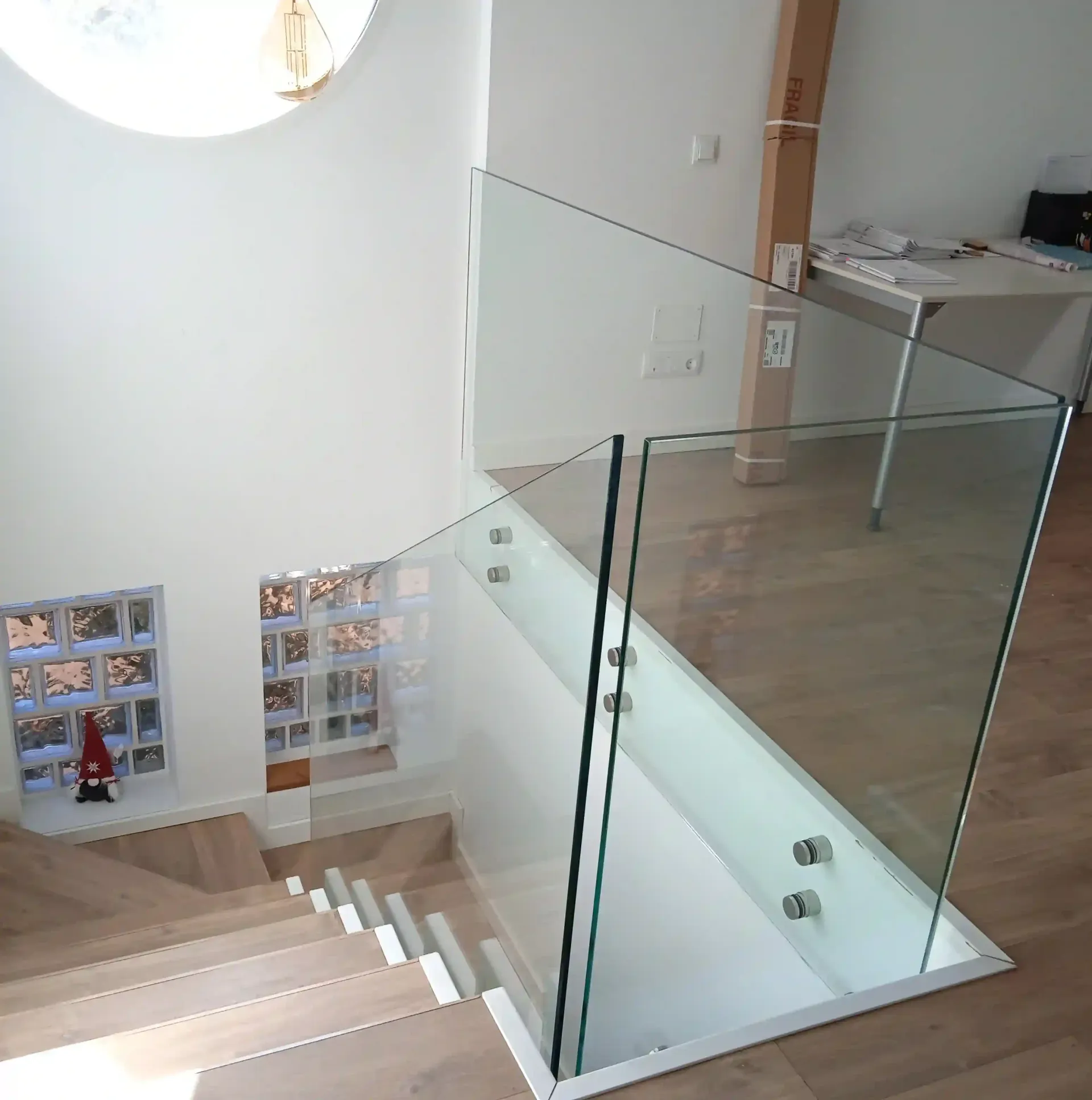 Una escalera con barandilla de vidrio que conduce al segundo piso.