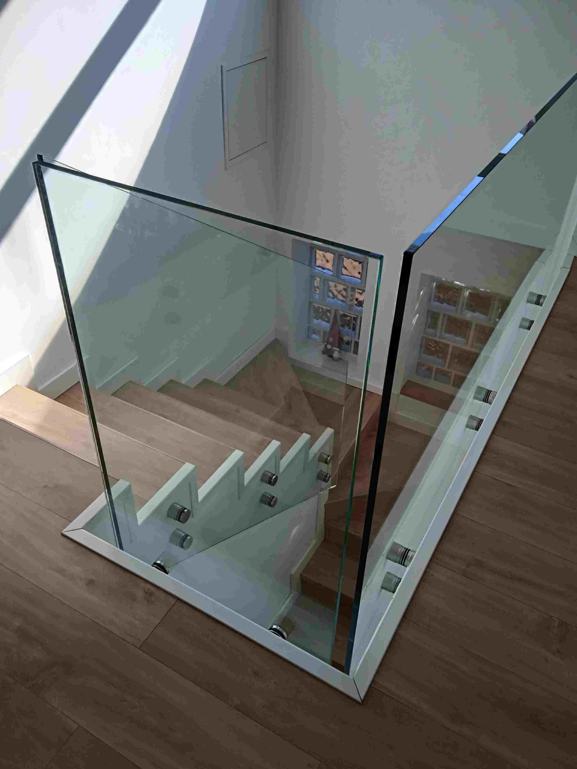 Una escalera con barandilla de cristal y escalones de madera.