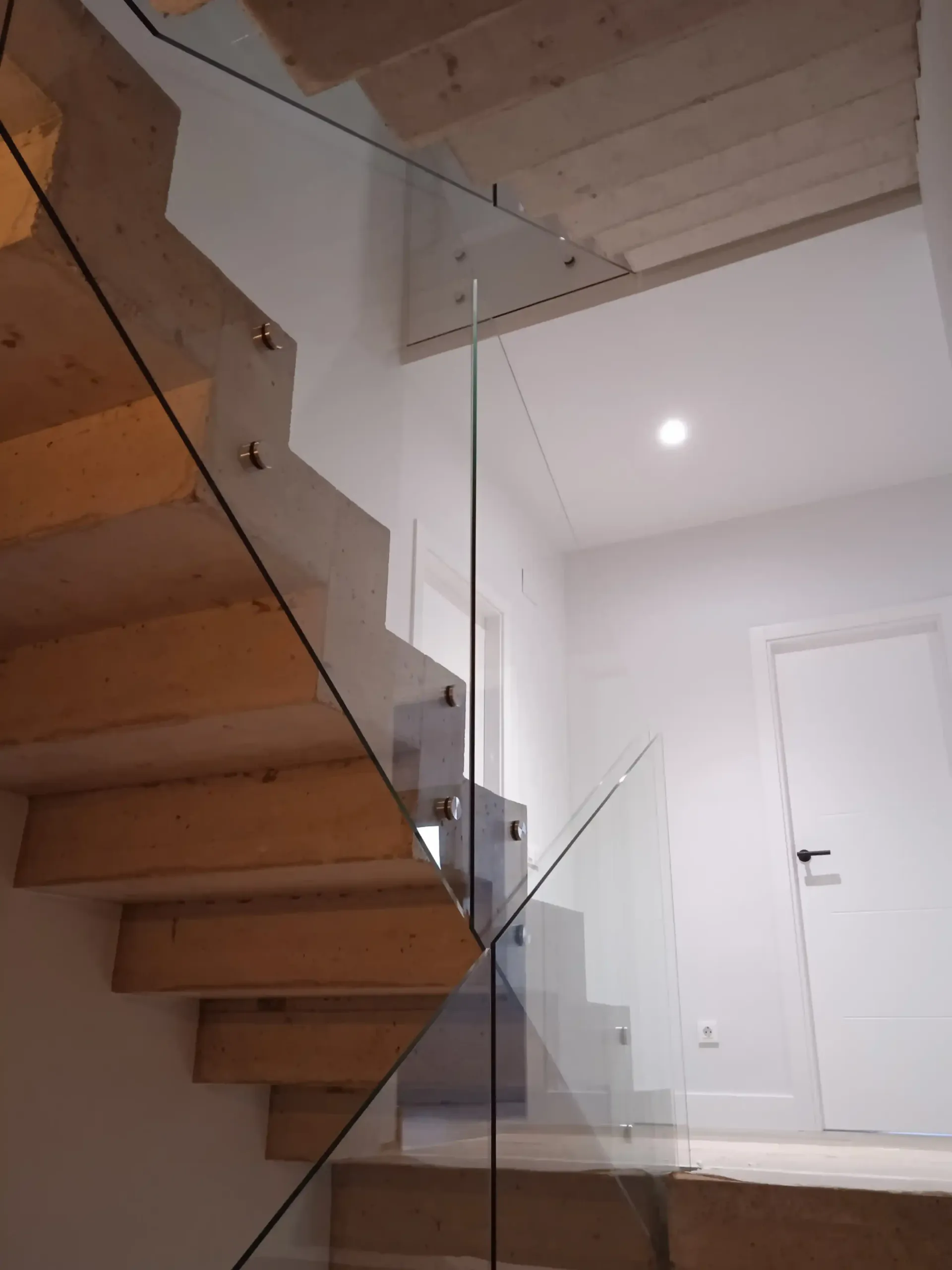 Una escalera de madera con barandilla de cristal en una casa.
