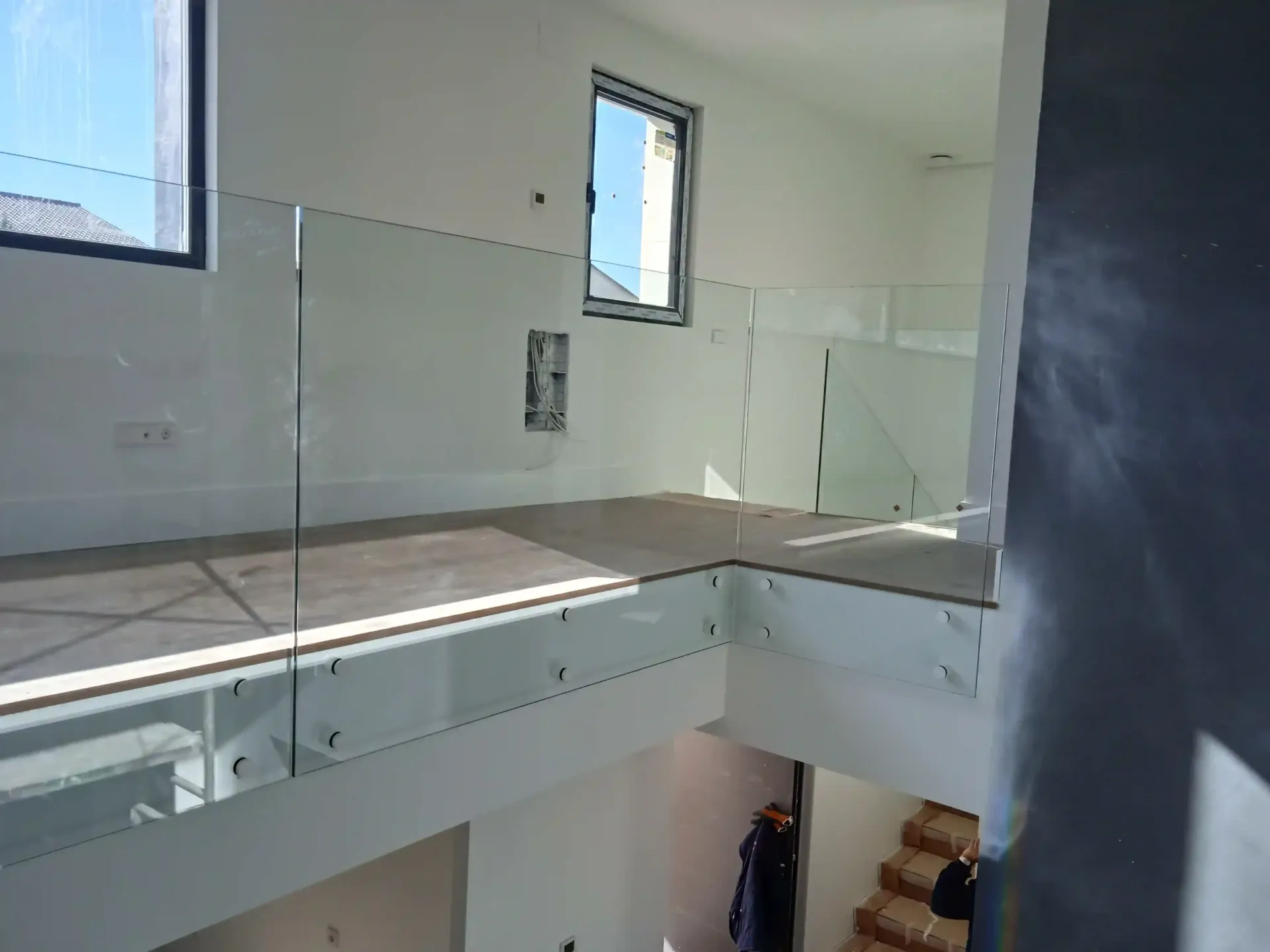 Una escalera con barandilla de cristal y una ventana.