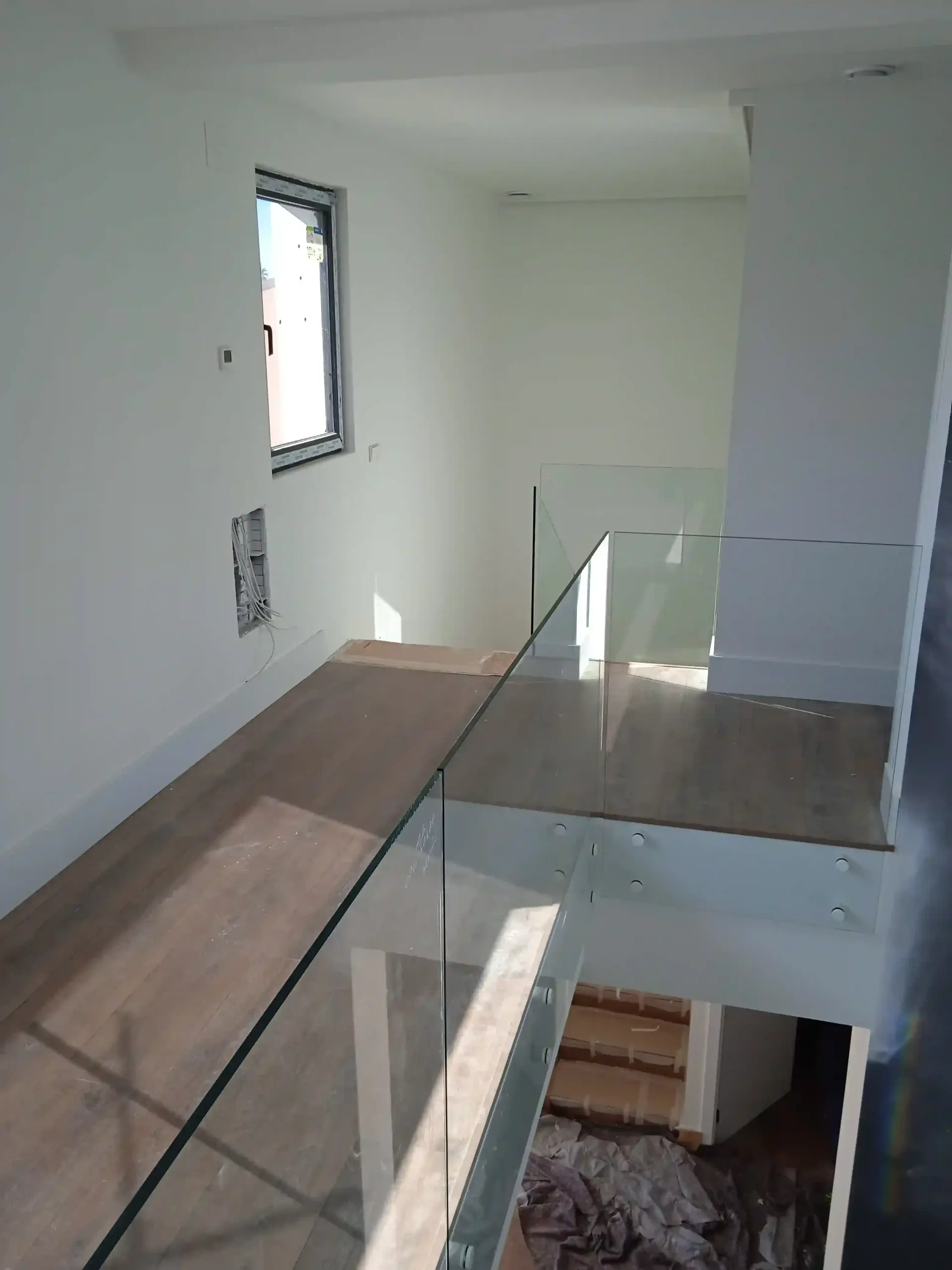 Una habitación vacía con una barandilla de cristal y una ventana.