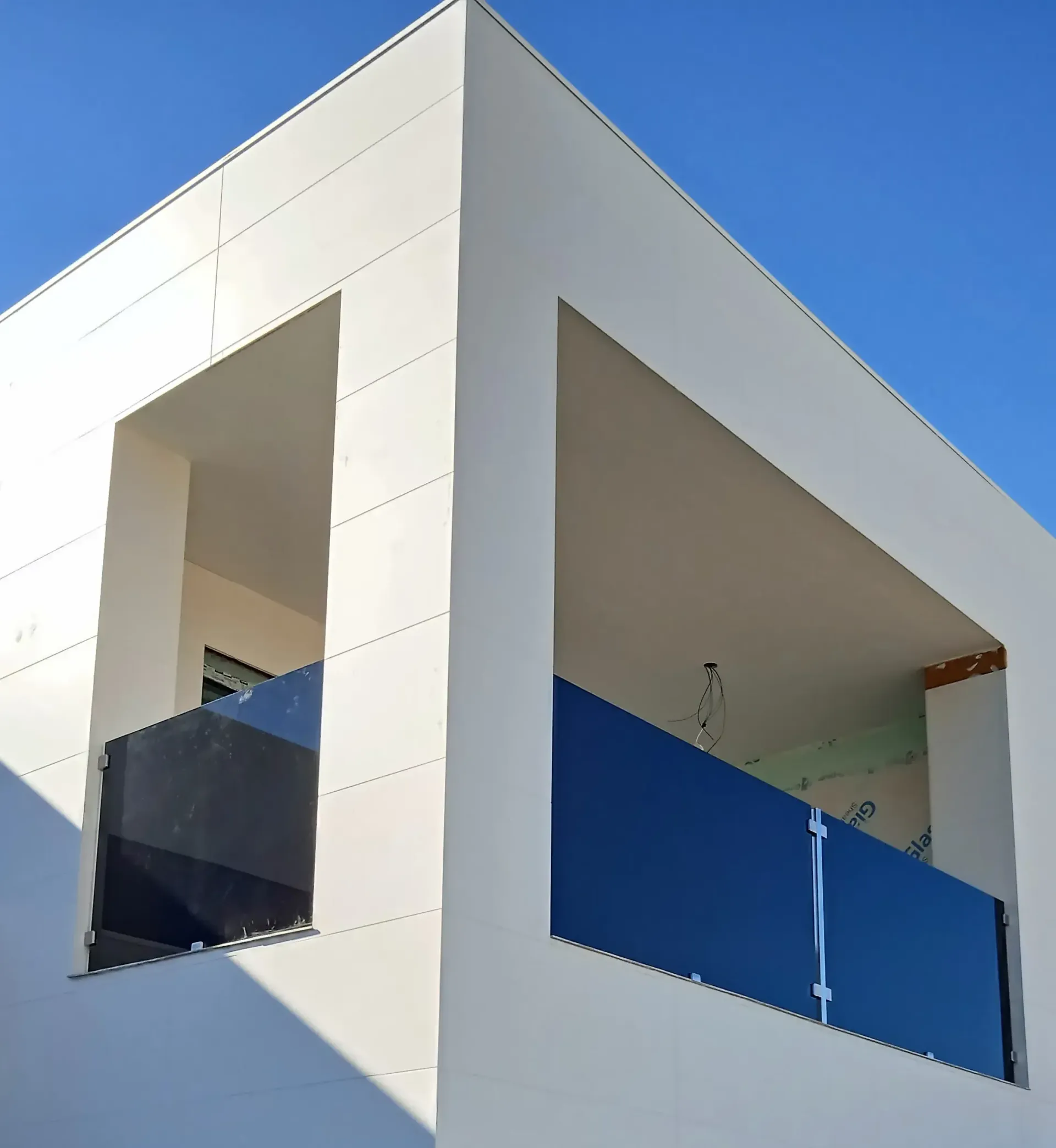 Un edificio blanco con un balcón y una barandilla azul.