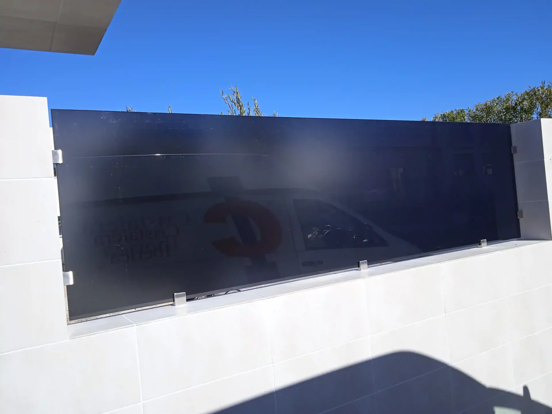 Una pared de ladrillo blanco con una valla negra delante.