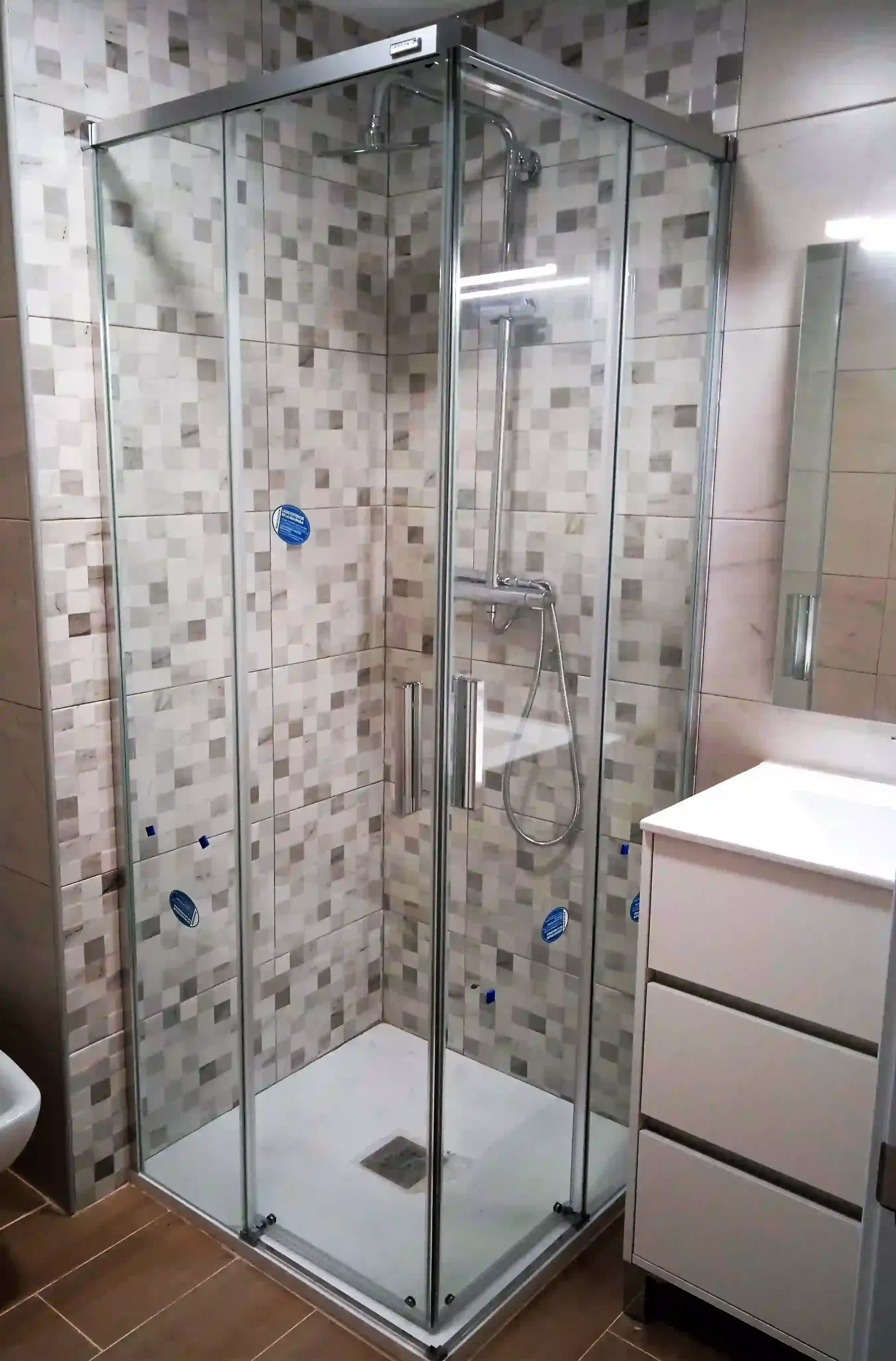 Un baño con cabina de ducha, lavabo y espejo.