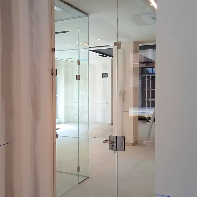 Un pasillo con una puerta de cristal que conduce a una habitación.