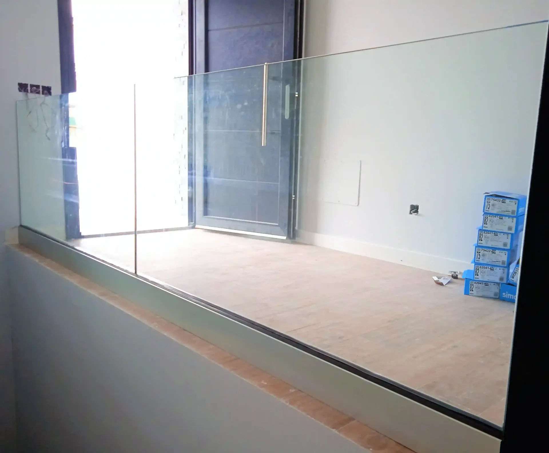 Una habitación con una barandilla de cristal y una puerta al fondo.