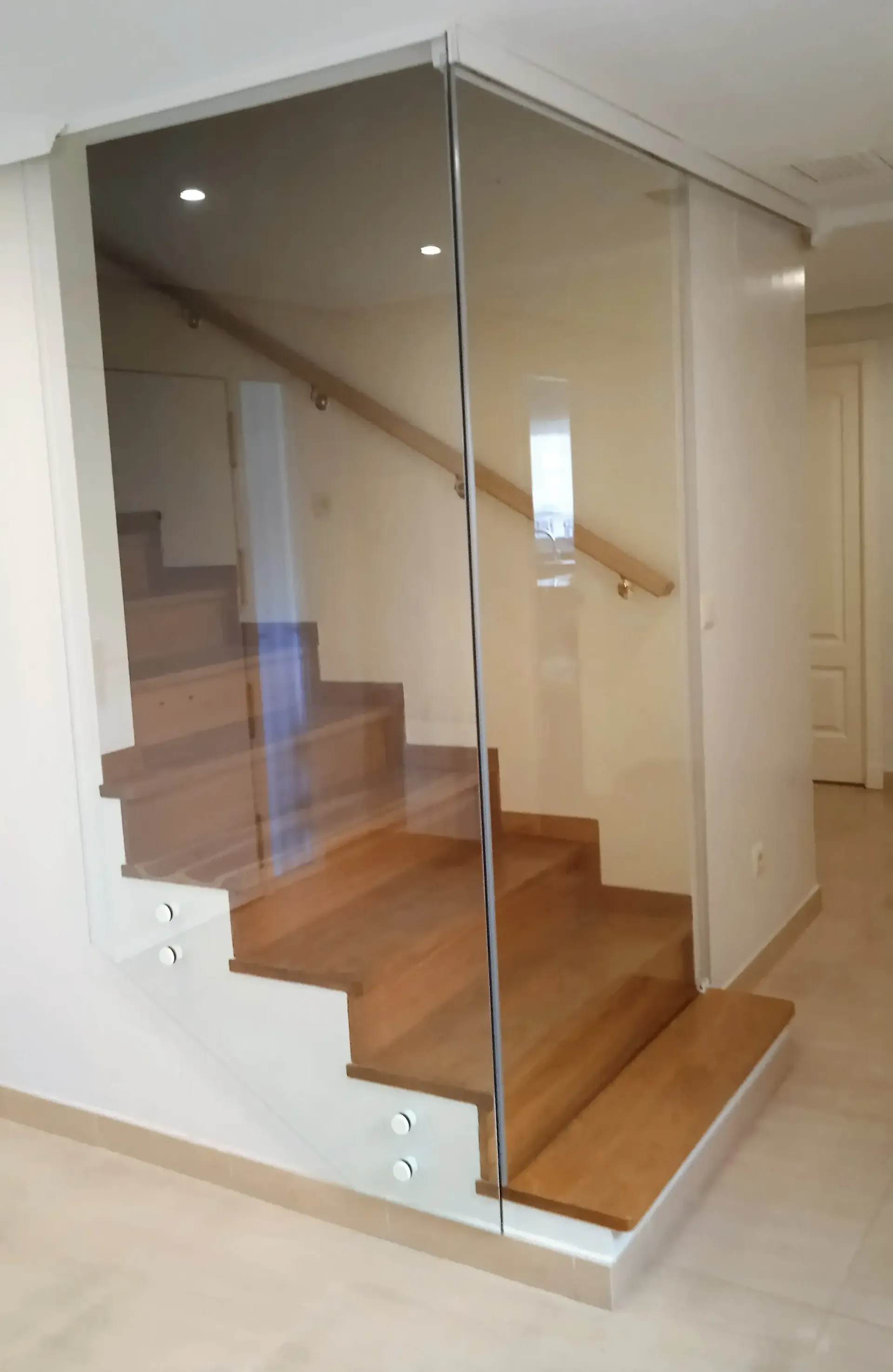 Una escalera con escalones de madera y barandilla de cristal.