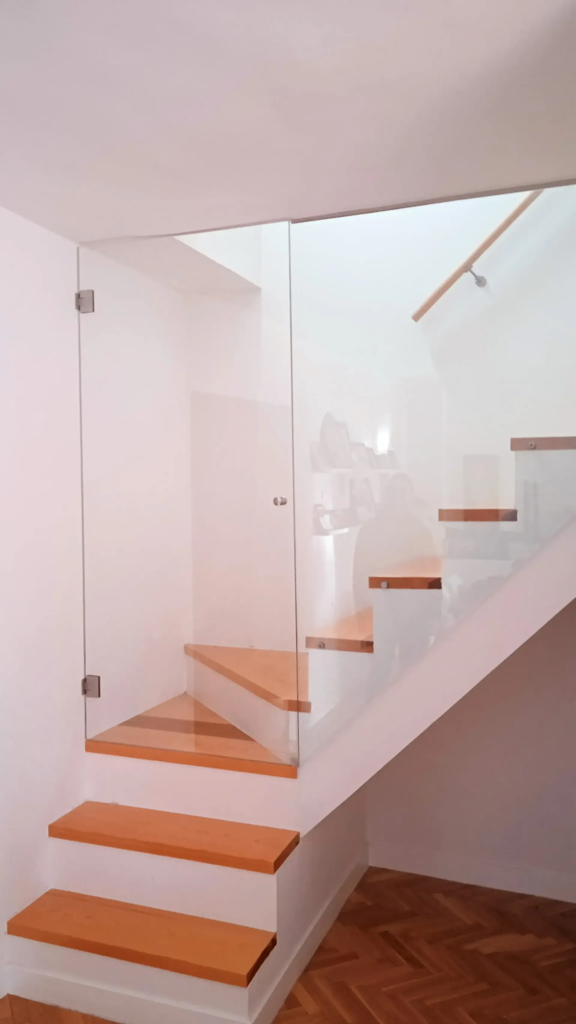 Una escalera con escalones de madera y barandilla de cristal.