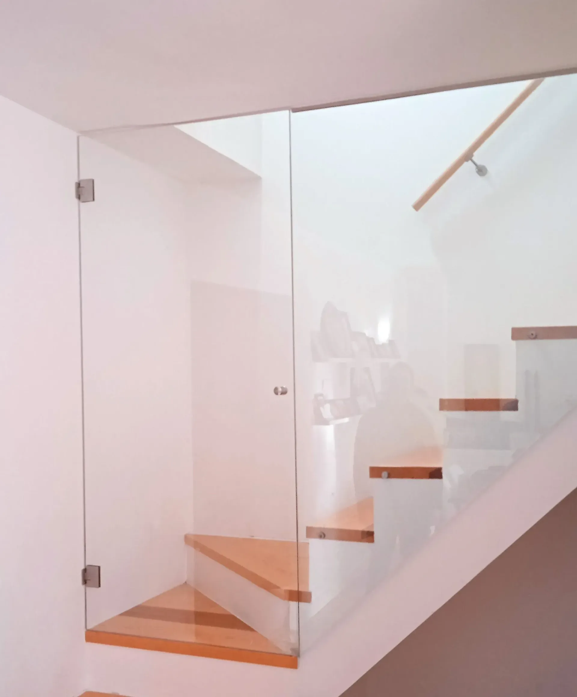 Una escalera con barandilla de cristal y escalones de madera.