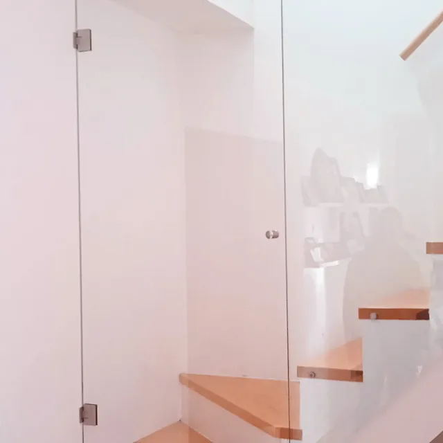 Una escalera con barandilla de cristal y escalones de madera.
