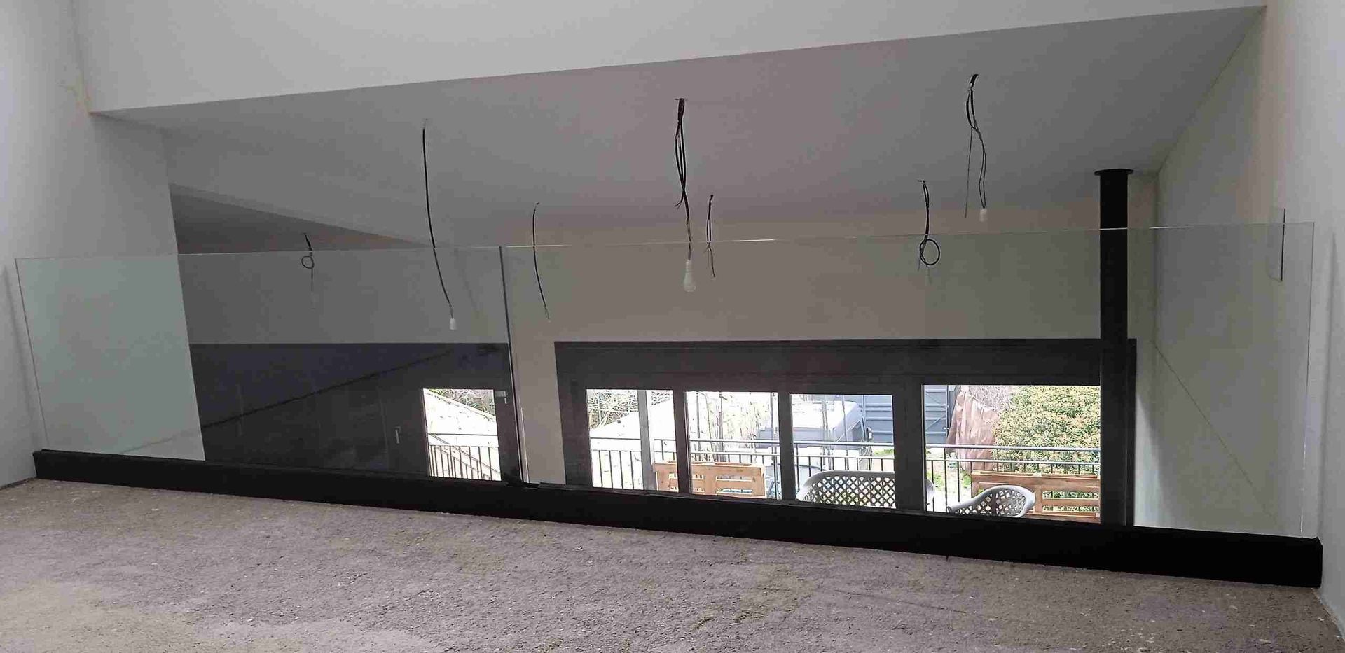 Una gran habitación vacía con balcón y muchas ventanas.