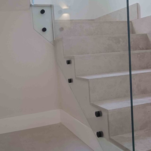 Un primer plano de una escalera con barandilla de vidrio.