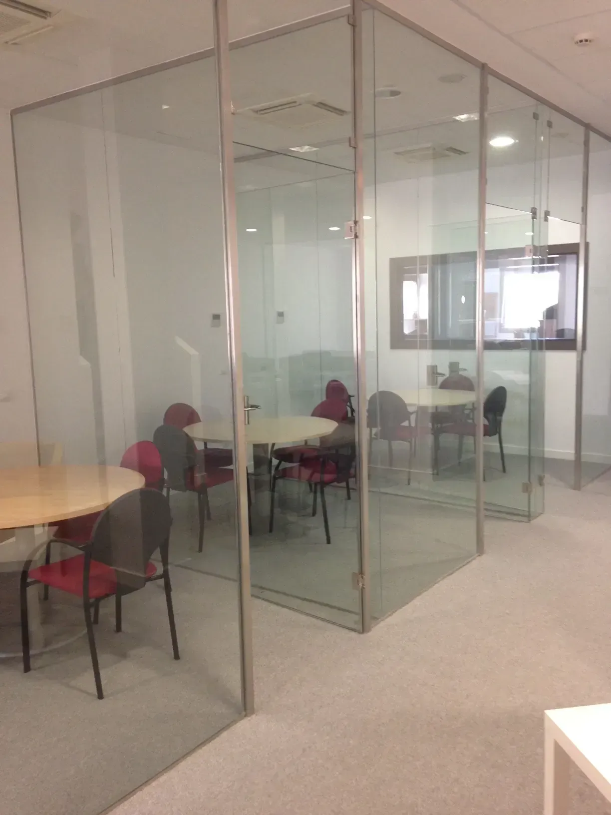Una habitación con mesas y sillas detrás de paredes de cristal.