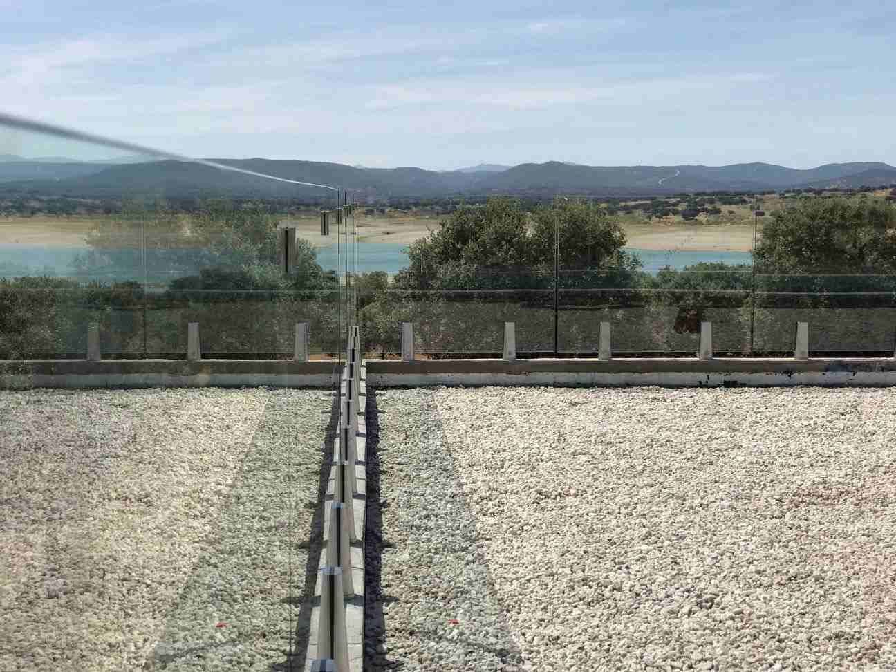 Una vista de un lago desde un balcón con barandilla de vidrio.