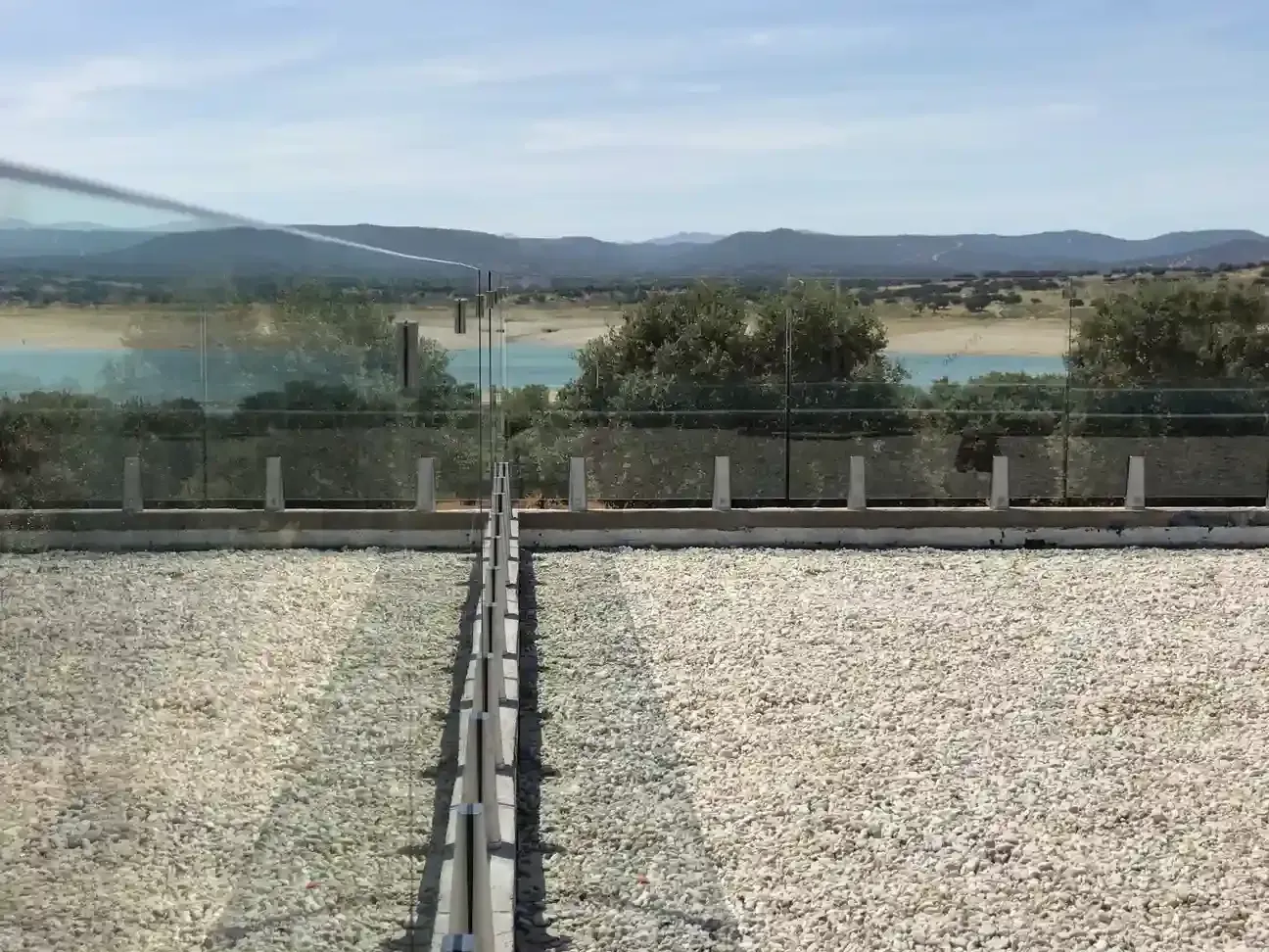 Una vista de un lago desde un balcón con barandilla de vidrio.