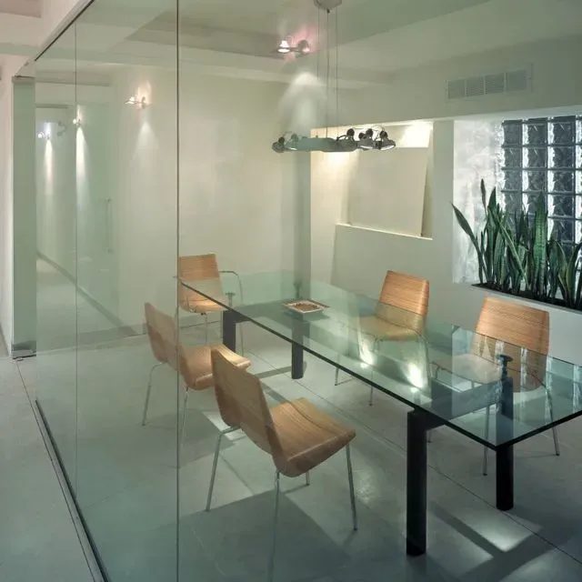 Un comedor con una mesa de cristal y sillas.