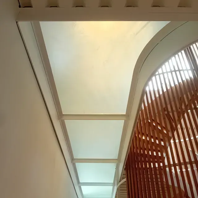 Una escalera con barandilla de madera y techo blanco.