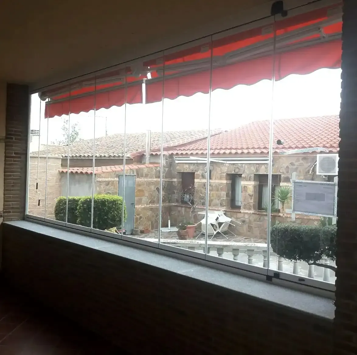 Una gran ventana con un toldo rojo encima.