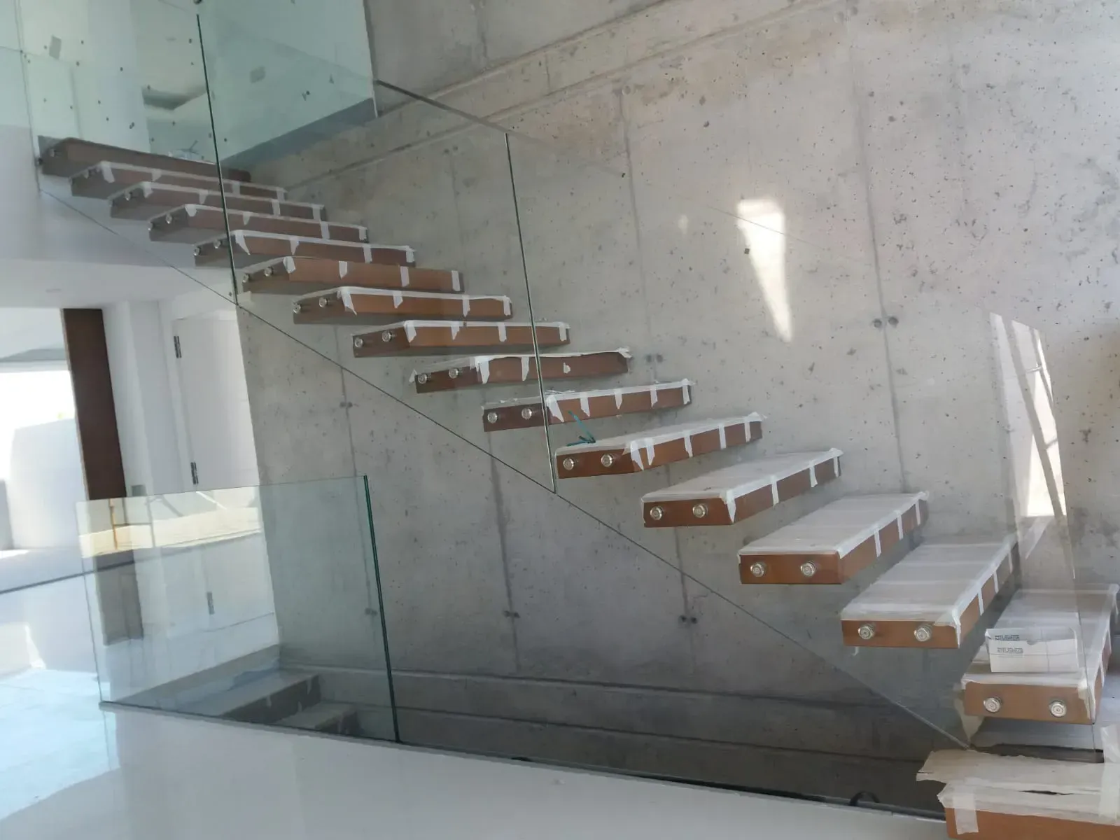 Una escalera con escalones de madera y barandilla de cristal.