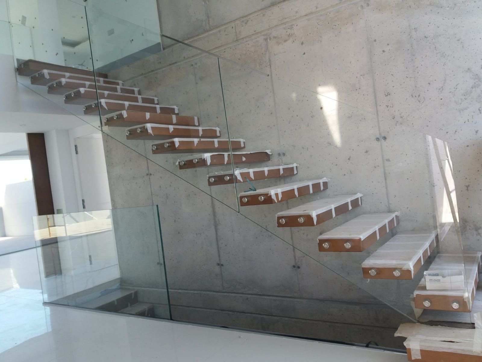 Una escalera con escalones de madera y barandilla de cristal.