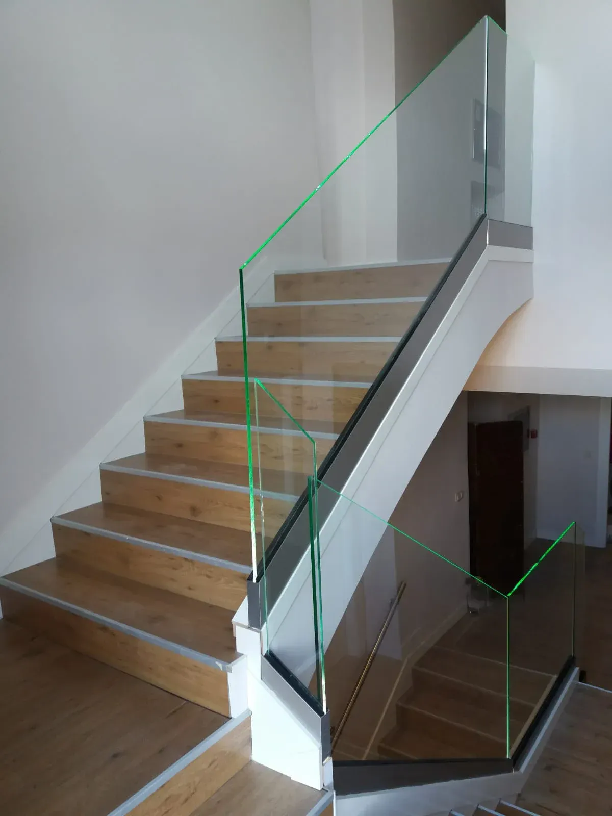 Una escalera con escalones de madera y barandilla de cristal.