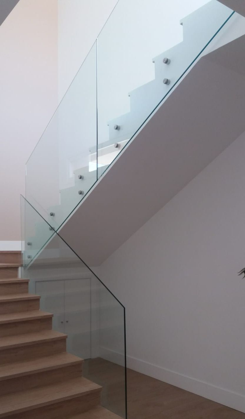 Una escalera con barandilla de cristal y escalones de madera.