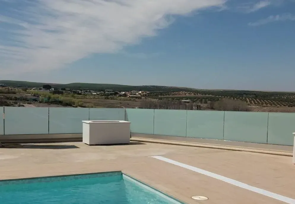 Una gran piscina con una valla de cristal a su alrededor.