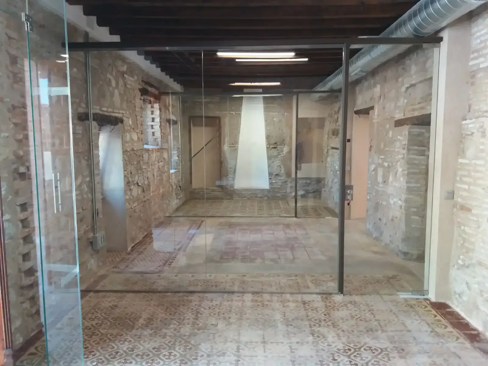 Un pasillo con una pared de cristal y una pared de ladrillo.