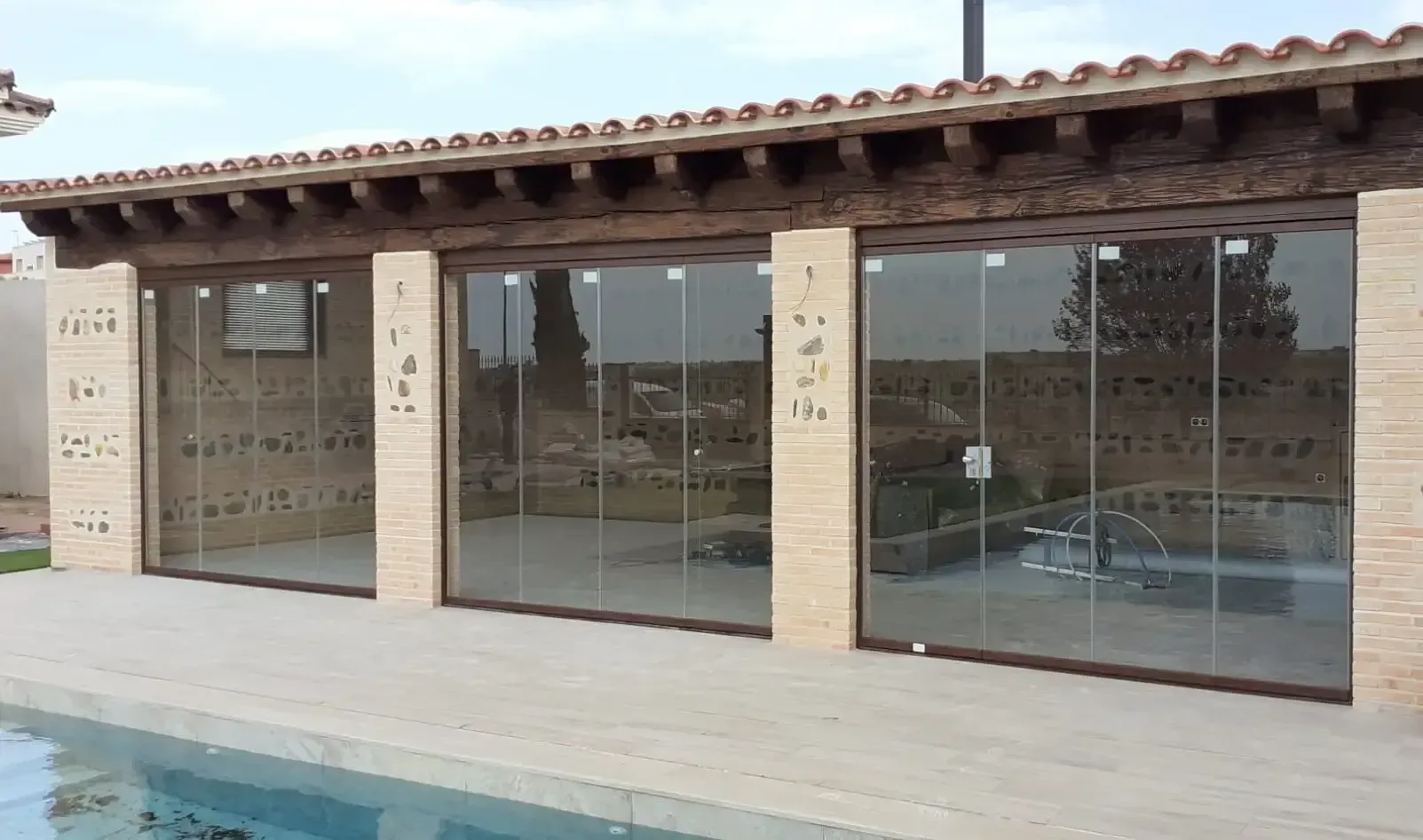 Una casa con puertas corredizas de vidrio y una piscina al fondo.