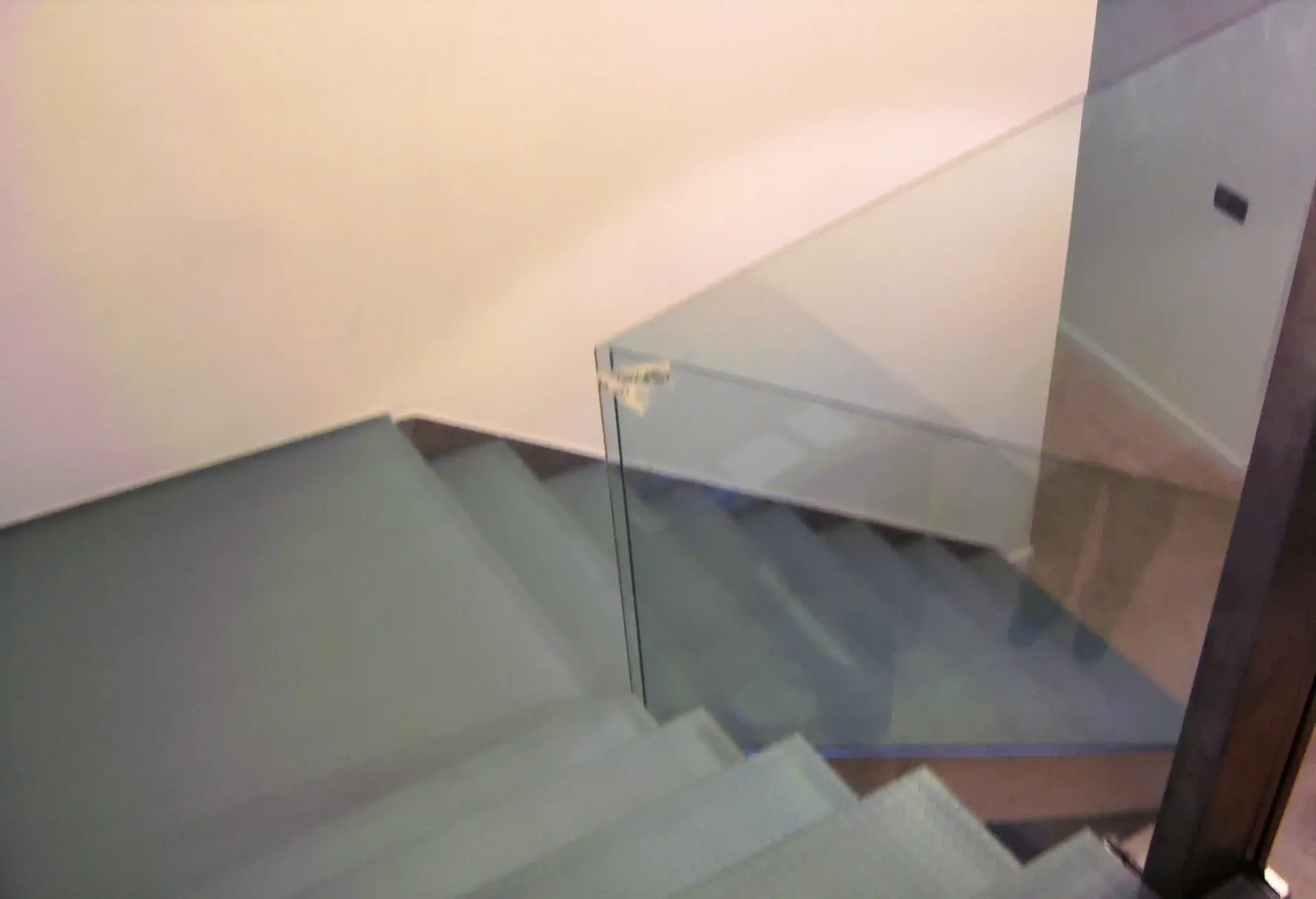 Un primer plano de una escalera con barandilla de vidrio.