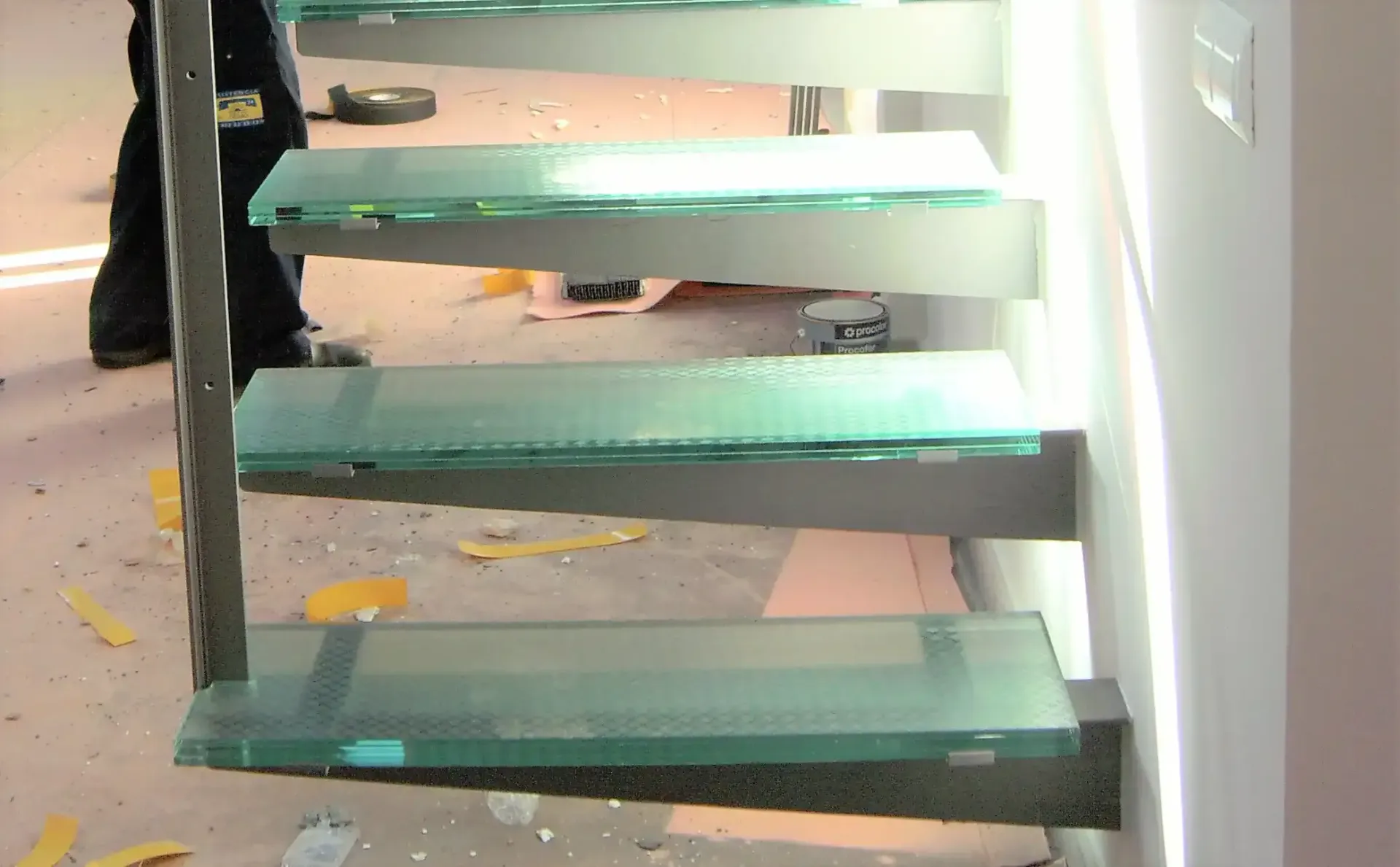 Una persona está parada al lado de unas escaleras de cristal.
