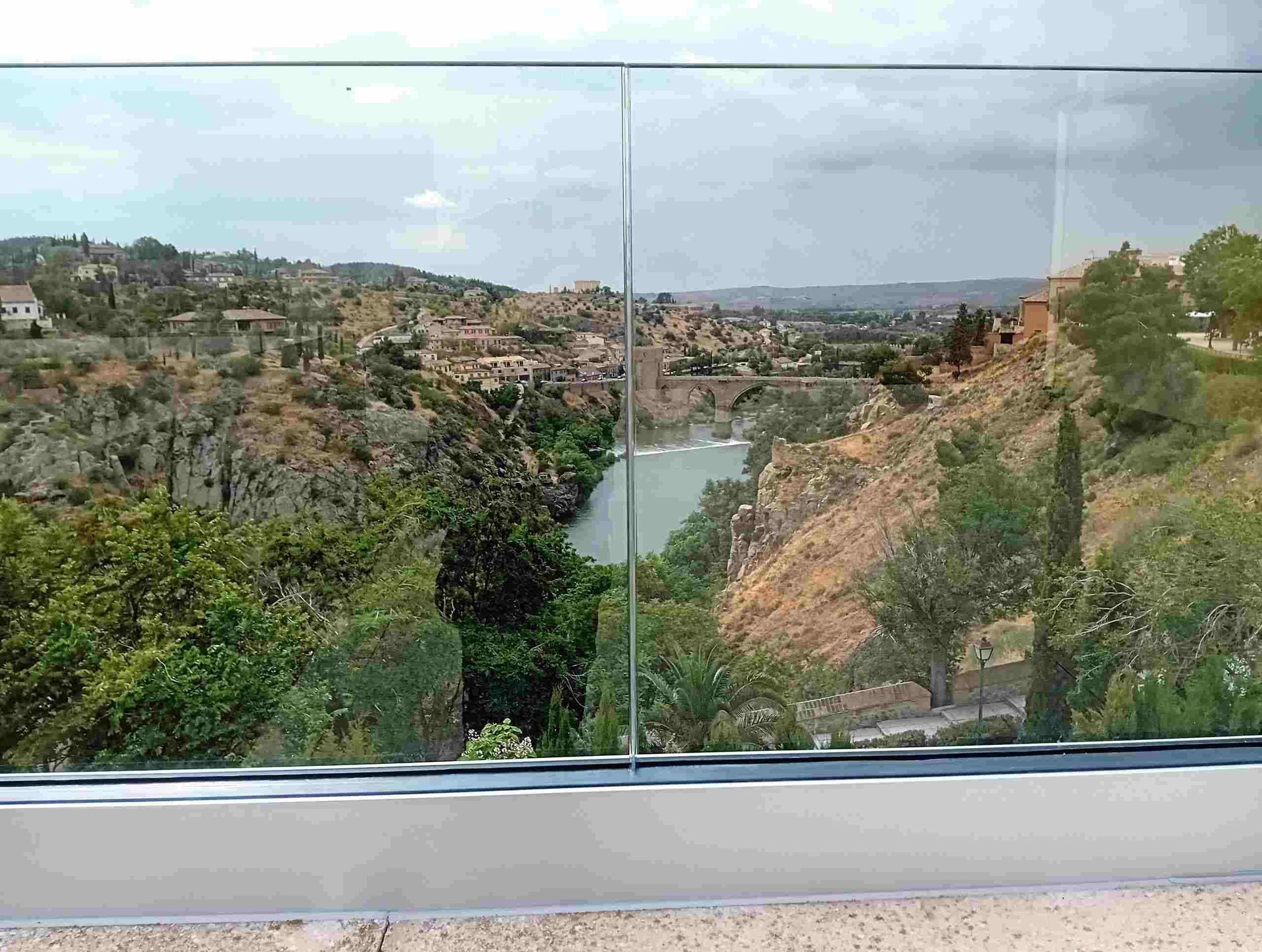 Una vista de un río desde un balcón con barandilla de vidrio.