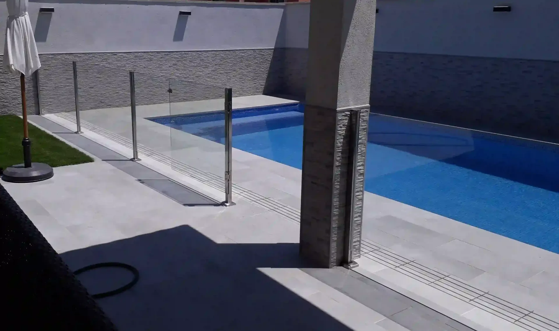 Una gran piscina con una valla de cristal a su alrededor.