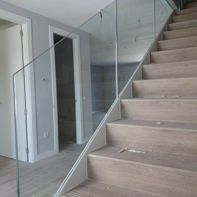 Un conjunto de escaleras con barandilla de vidrio transparente.