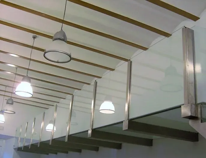 Un techo con vigas de madera y una barandilla de cristal.