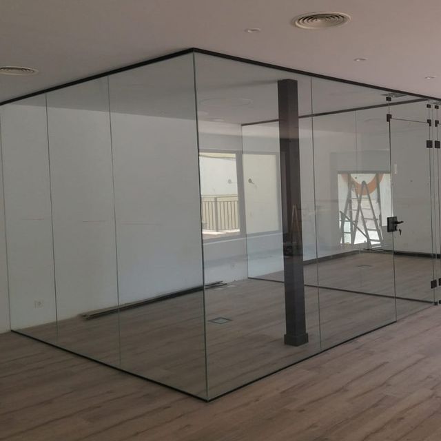 Una habitación con muchas paredes de cristal y suelo de madera.