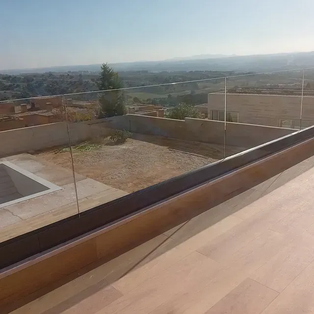 Una vista de una piscina desde un balcón con barandilla de cristal.