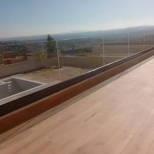 Una vista de una piscina desde un balcón con barandilla de cristal.