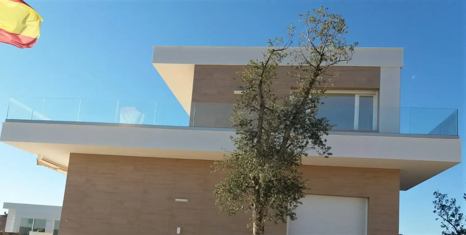 Una casa grande con un balcón y un árbol delante.