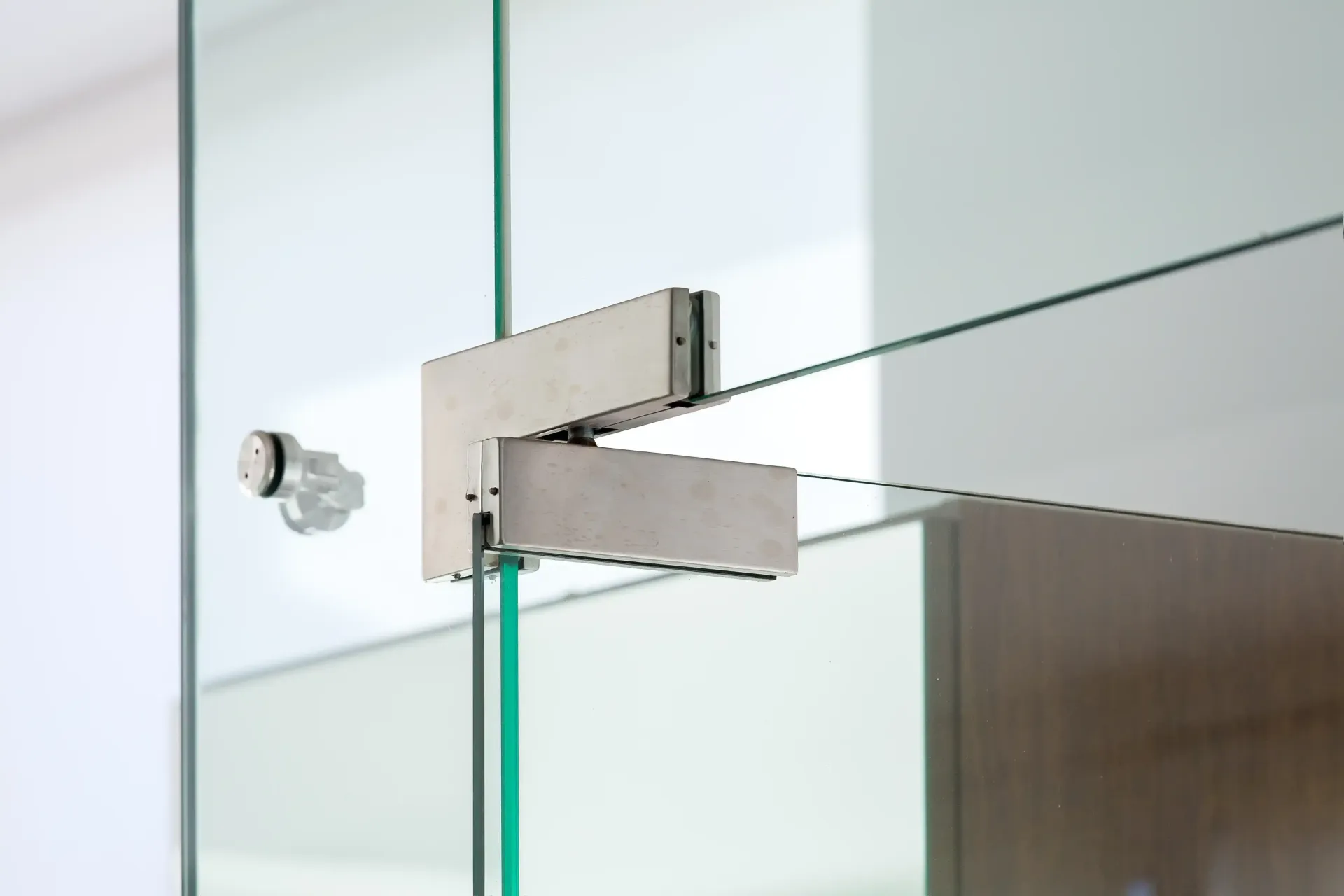 Un primer plano de una puerta de vidrio con una bisagra de acero inoxidable.