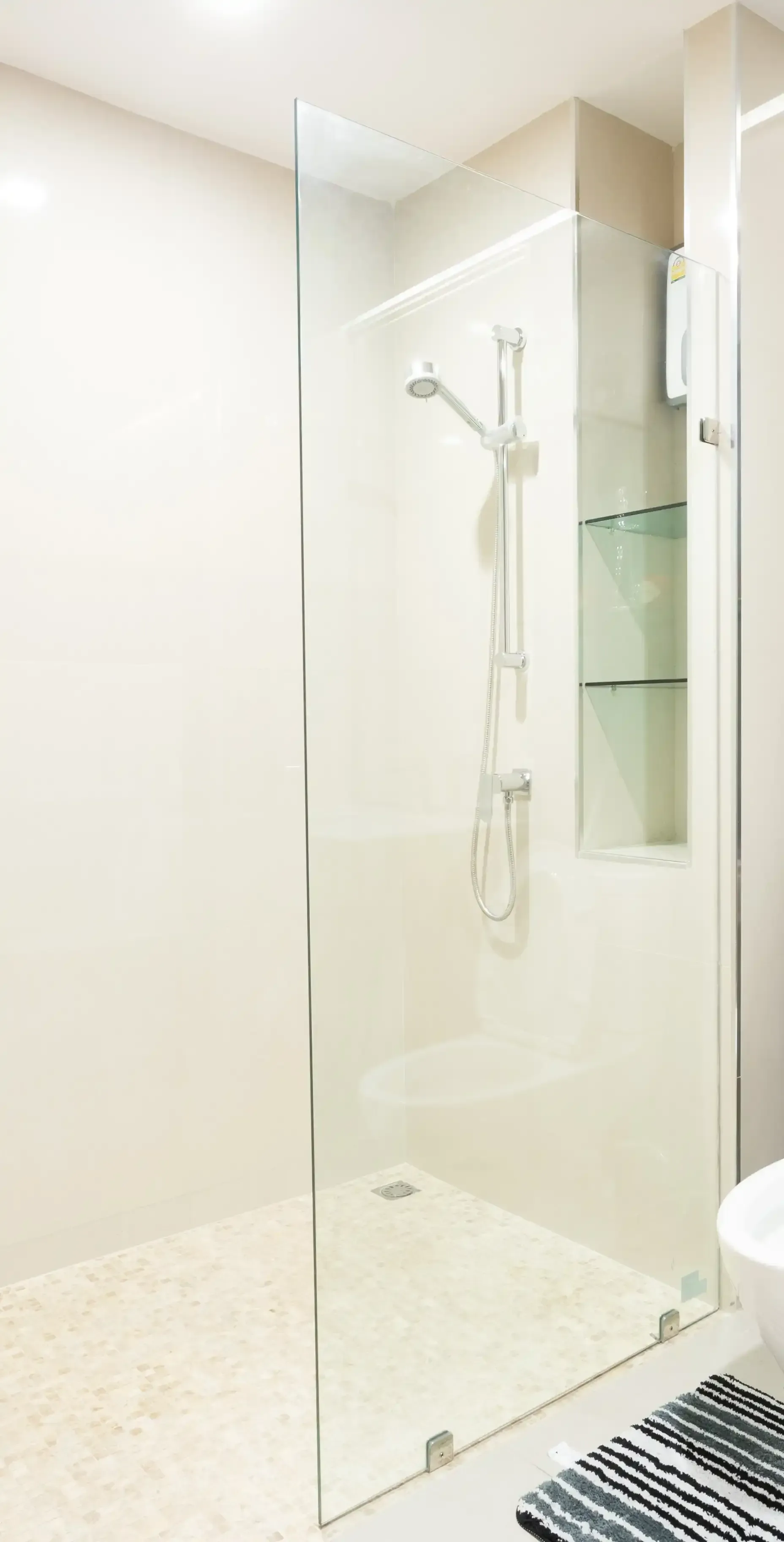 Un baño con ducha a ras de suelo y puerta de cristal.