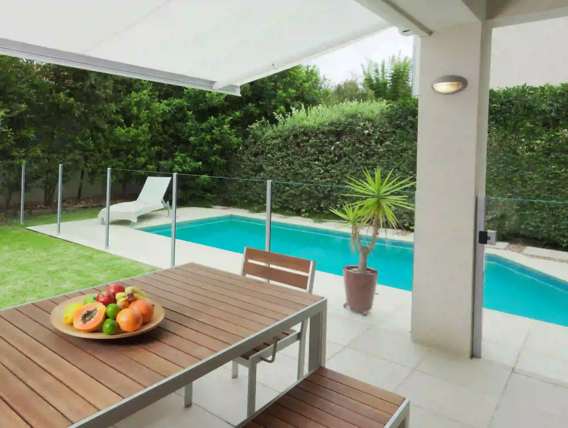 Una mesa con un bol de fruta junto a una piscina.