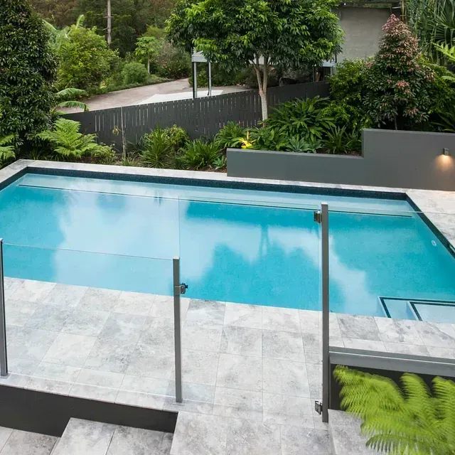 Una gran piscina con una valla de cristal a su alrededor.